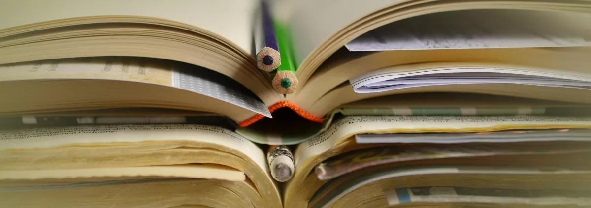 Livres ouverts empilés et crayons de couleur